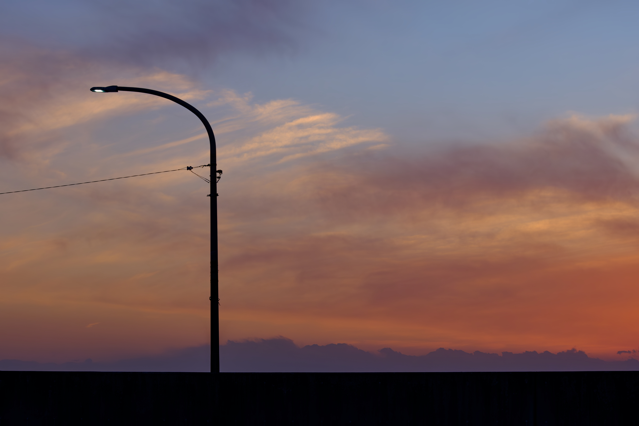 夕暮れの空を防波堤越しに